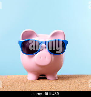 Pink piggy bank beach travel vacation savings sunglasses. Stock Photo