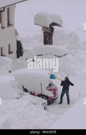 man shovels snow from his completely covered by snow Stock Photo