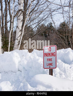'No Parking Fire Lane' sign on snow bank near the Sacandaga River in Speculator, NY keeping the area open for fire trucks to draw water from the river Stock Photo