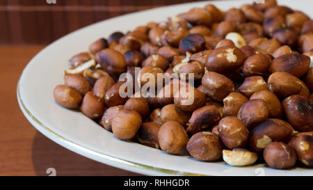 Roasted Peanuts Snack in White Plate in Wooden Backgrounds - Тopview ans Closeup Stock Photo