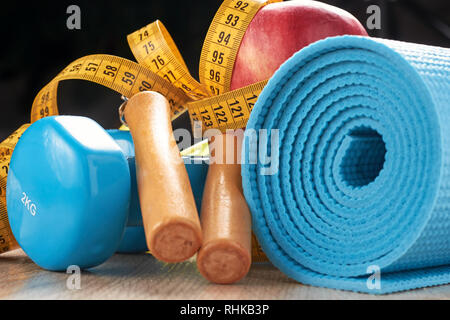 Fitness concept with blue dumbbells, fitness mat and skipping rope on dark background Stock Photo