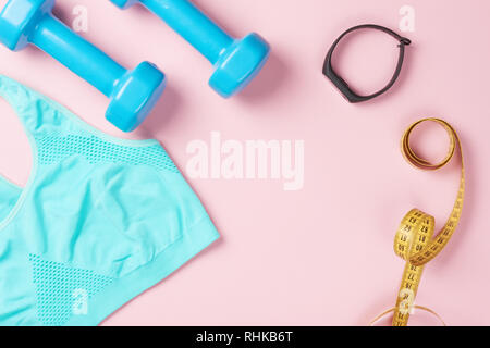 Sport bra, dumbbells, measuring tape and fitness tracker on pink background, top view with copy space. Fitness and body care concept Stock Photo