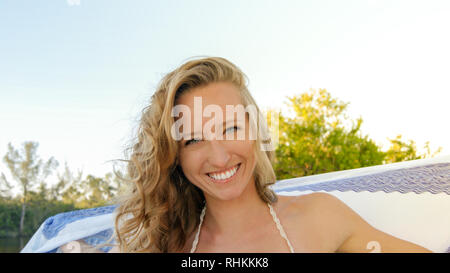 Portrait of a young normal blonde woman happy and smiling with blue eyes in nature with a white and blue mandala scarf Stock Photo