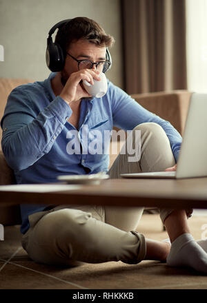 young people working at home- business man uses a laptop and drinking coffee Stock Photo