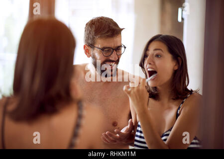 Happy couple brushing their teeth in the bathroom. Stock Photo
