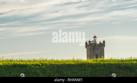 Saint Julian Fortress lighthouse tower standing behind empty land with green grass Oeiras, Lisbon Stock Photo