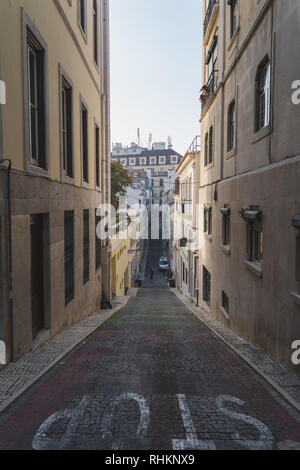 Long and narrow street in chiado Lisbon, Portugal. Elevation, ramp, hill going up and down. Slope with steep inclination. Stop written on the road. Stock Photo