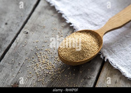 Amaranth seeds in a wooden spoon on table, selective focus. Raw Organic Amaranth Grain. Stock Photo