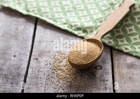 Amaranth seeds in a wooden spoon on table, selective focus. Raw Organic Amaranth Grain. Stock Photo