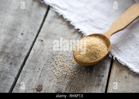 Amaranth seeds in a wooden spoon on table, selective focus. Raw Organic Amaranth Grain. Stock Photo