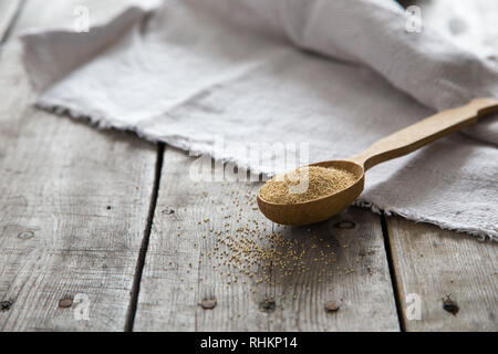 Amaranth seeds in a wooden spoon on table, selective focus. Raw Organic Amaranth Grain. Stock Photo