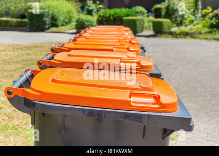 Row of gray with orange waste containers for packaging material along the street Stock Photo