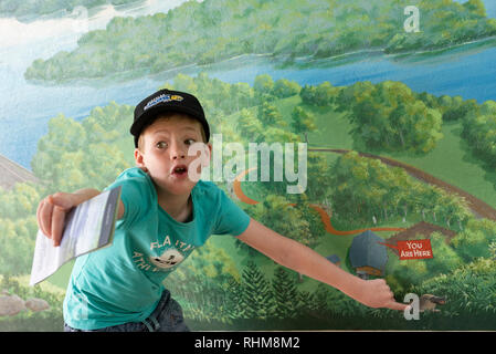 Boy excited about a platypus on an illustration at Rocky Creek Dam, rainforest and water reserve, New South Wales, Australia and points at something Stock Photo