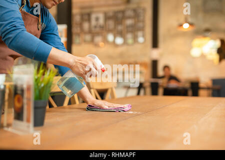 Waiter cleaning the table with spray disinfectant on table in restaurant.  Stock Photo