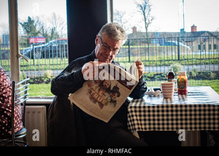 senior man sitting in a cafe reading a newspaper Stock Photo