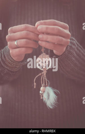 Two caucasian female hands holding a dream catcher in vintage filter colors mood - freedom and hope concept for hippy and indian people - closeup Stock Photo