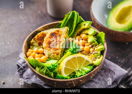 Vegan lunch in a coconut bowl: green burgers with salad and chickpeas. Healthy vegan food concept. Stock Photo