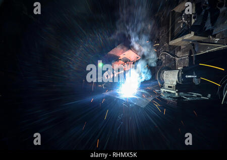 Operator, welder or worker welding some metal with welding machine behind the welding mask in the factory. Industrial concept image. Stock Photo