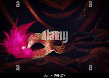 Photo of elegant and delicate gold, red venetian mask over dark velvet and silk background Stock Photo