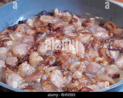 Preparation of Uzbek pilaf - roasting meat in oil, zirvak, close-up Stock Photo