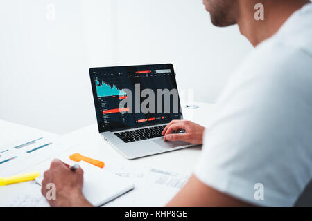 Creative building designer working with drawing plan and computer while sitting by table at studio office. Young architect using laptop and blueprint  Stock Photo