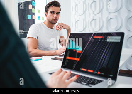 Two young coworker working toogether at work place office while sitting at the table. Team of business people analyze document and blueprint plan Stock Photo