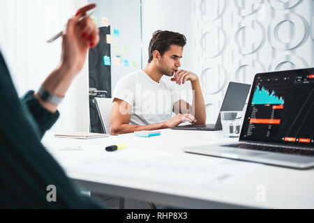 Сolleagues analyze digital reports on screen monitor and preparing financial report for investors. Team of business man and woman managers sitting at  Stock Photo