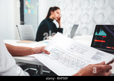 Young man designer and woman sitting in office and working on notebook. Group of coworkers looking at computer monitor while working in office Stock Photo