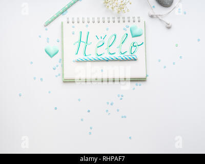 Spring girl's items flat lay on white. Hello word written on notebook