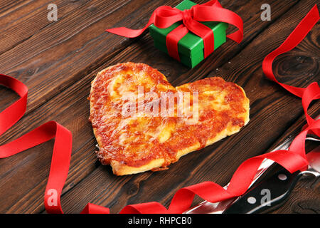 Valentines day pizza in heart shape on dark rustic wooden background.  Valentine heart pizza food Stock Photo