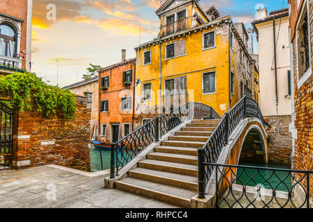 An empty square with a bridge in a quite residential area of Venice, Italy, with a blue boat docked in the canal in front of a home. Stock Photo