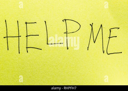 Help me. Macro photo of handwritten inscription on yellow paper Stock Photo