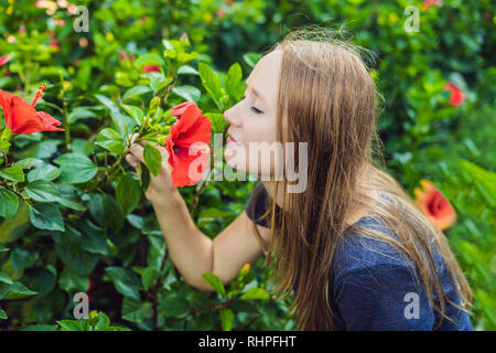 Young woman sniffing hibiscus in the park Stock Photo
