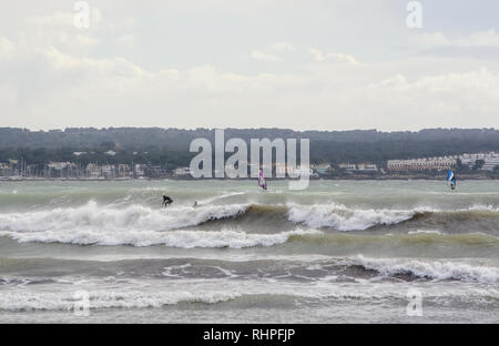 PALMA DE MALLORCA, SPAIN - FEBRUARY 2, 2019: Surfers ride big waves in the bay on a stormy gray afternoon on February 2, 2019 i Palma de Mallorca, Spa Stock Photo