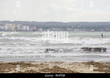 PALMA DE MALLORCA, SPAIN - FEBRUARY 2, 2019: Surfers ride big waves in the bay on a stormy gray afternoon on February 2, 2019 i Palma de Mallorca, Spa Stock Photo