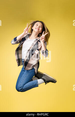 Vertical full length body size studio photo portrait of pretty careless successful glad lady student show her make v-sign near eyes face jumping up. Stock Photo