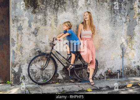 Mother and son on a bicycle. Public street art Name Children on a bicycle painted 3D on the wall that's two little Chinese girls riding bicycle in Stock Photo