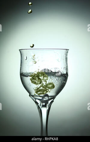 Oil splashing into a glass of water Stock Photo