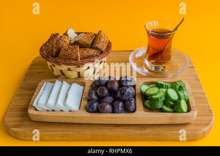 Typical Turkish breakfast of simit, cucumber, olives, and cheese, with Turkish tea, served in a glass. Stock Photo