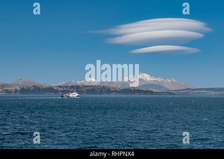 Ferry sailing between mainland Scotland and the Isle of Mull with snowcapped highland peaks in the background Stock Photo