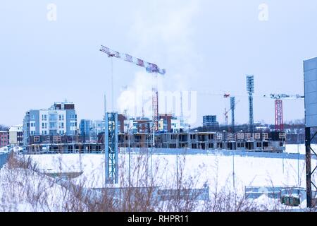 Against the background of houses that are under construction, smoke rises high from the chimney pipe. The house building industry in this century. Stock Photo