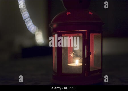 Red lantern with star on glass and burning tealight in darkness Stock Photo