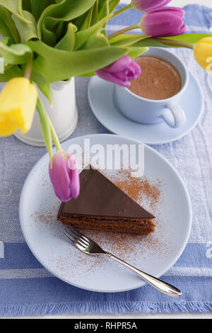 Chocolate cake, cup of coffee, and a bouquet of tulips Stock Photo