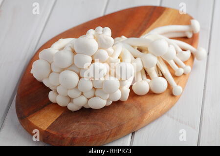 Bunch of raw Shimeji mushrooms also known as white beech mushrooms on a wooden cutting board Stock Photo