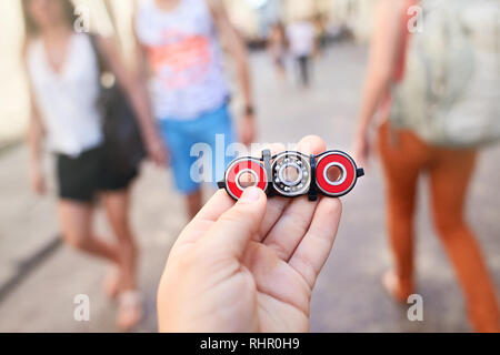 Closeup of hand of kid playing modern popular hand toy spinner made by himself by using screw-nuts and bearing. Child holding unusual metal spinner Stock Photo