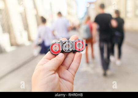Closeup of hand of kid playing modern popular hand toy spinner made by himself by using screw-nuts and bearing. Child holding unusual metal spinner Stock Photo