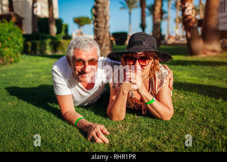 Senior couple lying on grass on hotel territory. Happy people enjoying vacation. Valentine's day Stock Photo