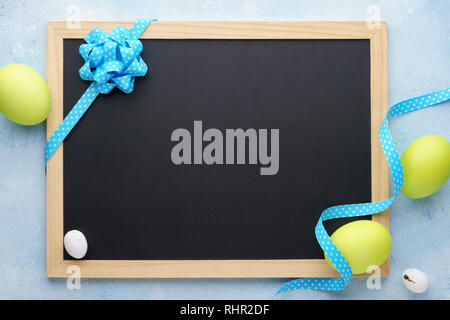 Easter frame with painted green eggs and empty chalkboard. Background with copy space. Stock Photo