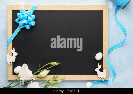 Easter frame background with chalkboard, flowers and cute wooden bunny. Blank space for text. Stock Photo