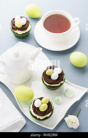 Easter chocolate cupcakes decorated with nest and candy eggs for dessert. Holiday table setting. Stock Photo